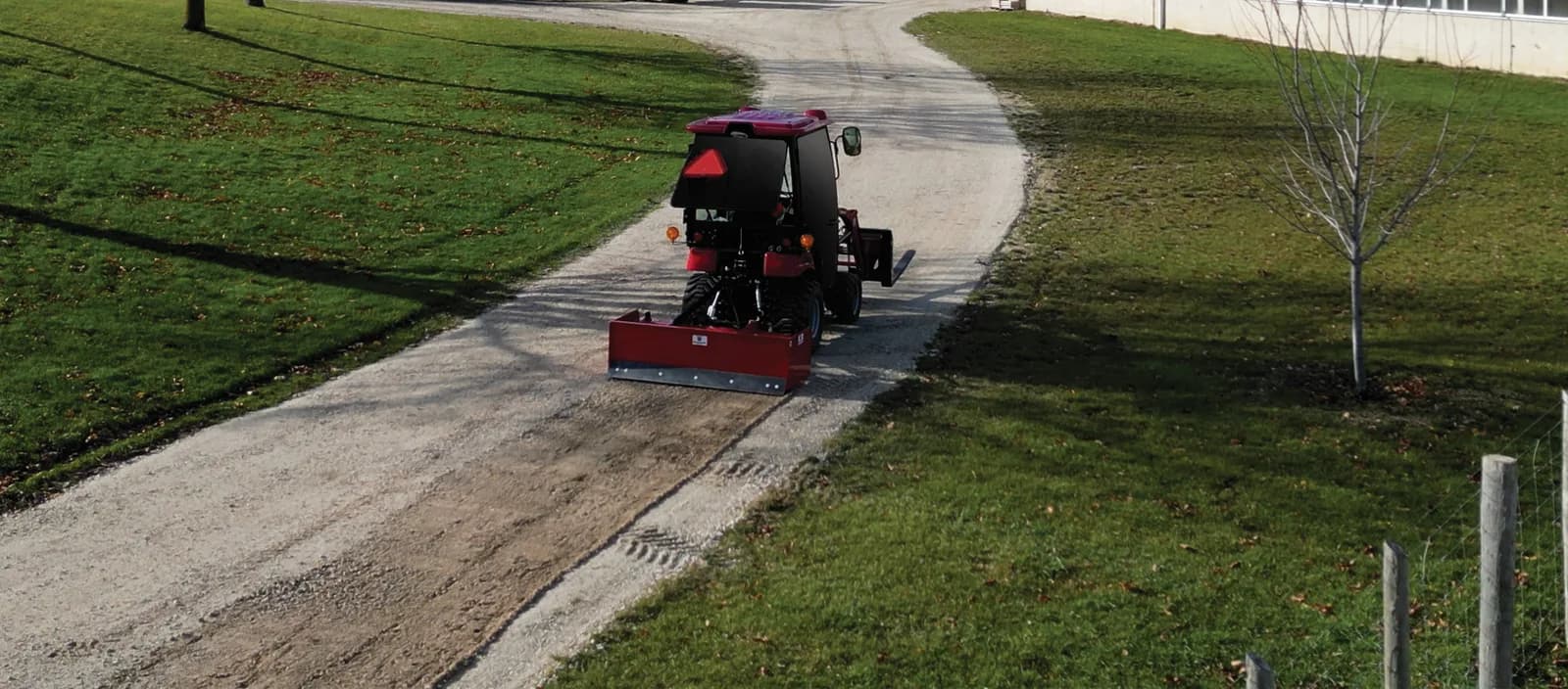 Skid steer grading a lane with a box blade